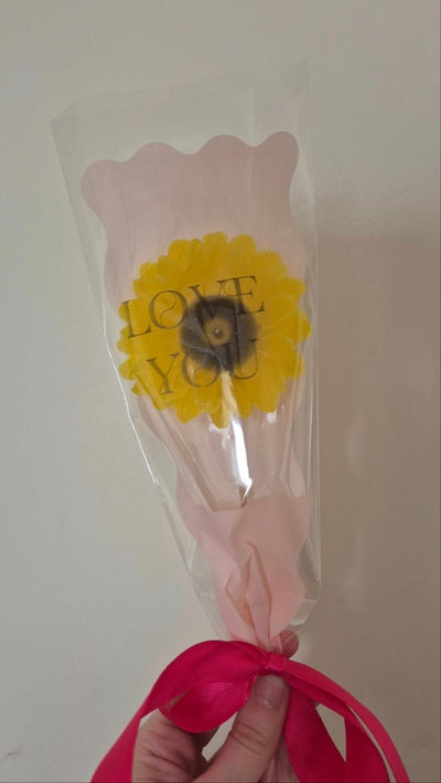 single sunflower wax melt in pink packaging  with pink ribbon wrapped around the bottom of the flower in a bow 