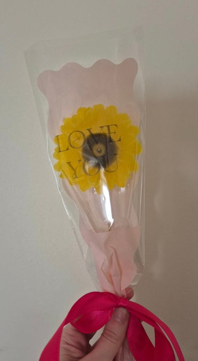 single sunflower wax melt in pink packaging with a pink ribbon around the bottom of the flower 