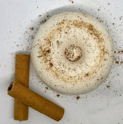 a white circular cinnamon shower steamer with short decorative cinnamon sticks  
