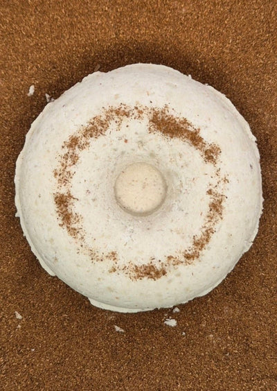a white circular cinnamon shower steamer with ground cinnamon as background 