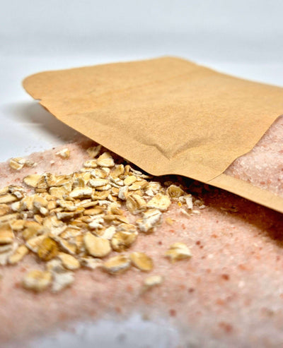 Oat bath salts spilling from an eco-friendly bag, featuring oats and pink mineral-rich salts for a soothing bath experience.