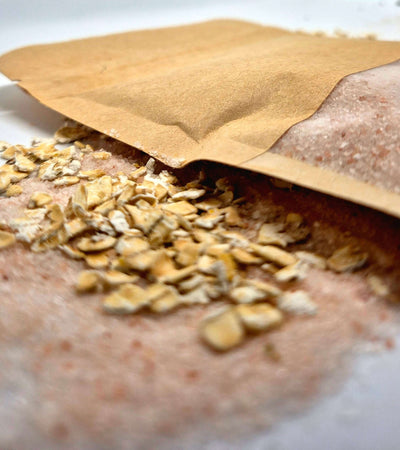 Oat bath salts spilling from a kraft bag with oats, perfect for relaxing and soothing bath rituals.